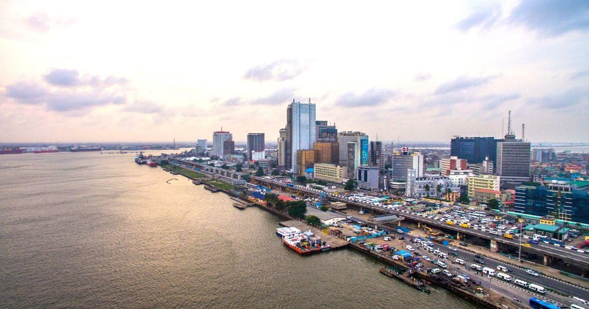 The Lagos Marina waterfront seen from above, the lagoon on the left and the towers and traffic of Lagos Island running along the shoreline