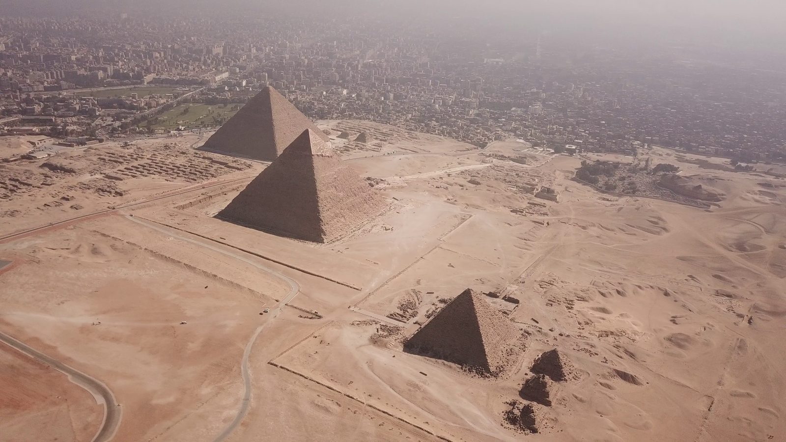 The pyramids of Giza from the air, the three of them on the desert plateau with the city running up to the edge of it