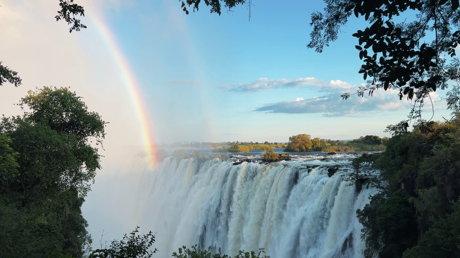 Victoria Falls seen along the gorge with a rainbow standing in the spray thrown up by the river